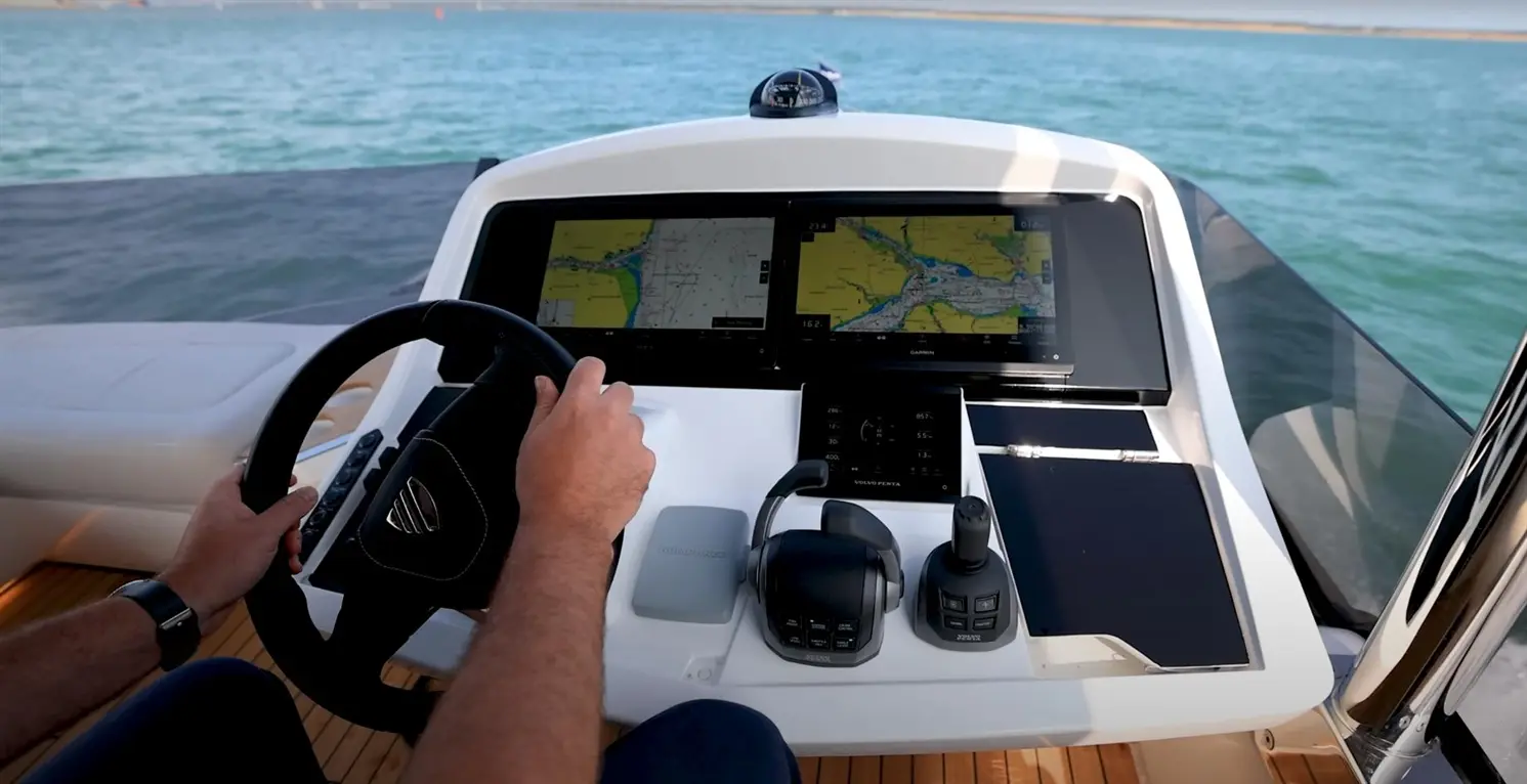 Steering a boat from a modern helm with dual screens showing navigational maps and controls for engines and systems.